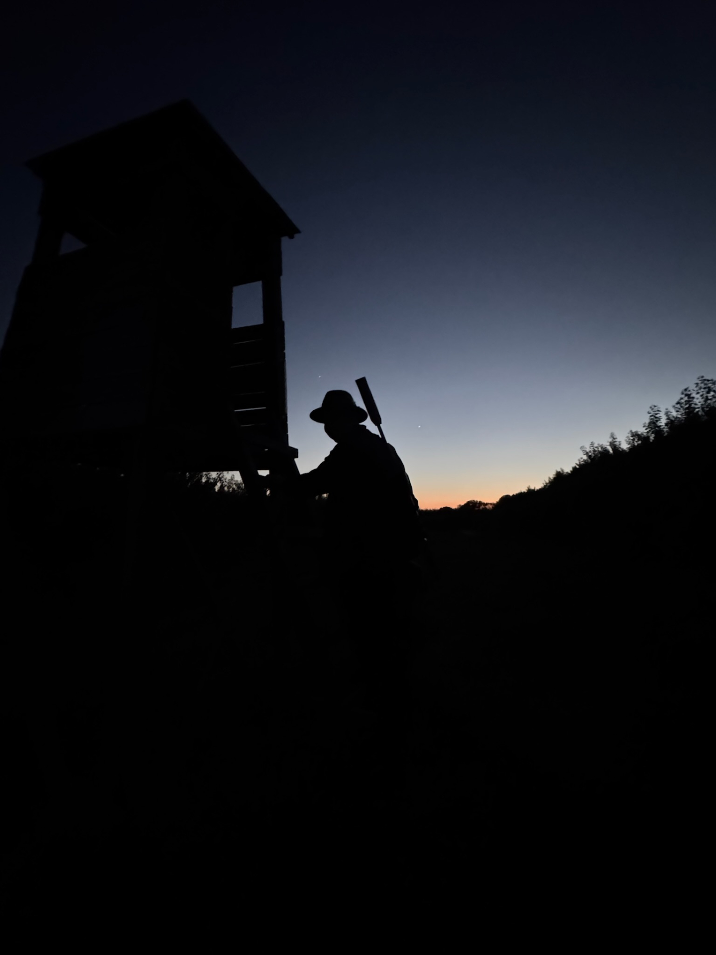 Jäger am Hochsitz in der Abenddämmerung
